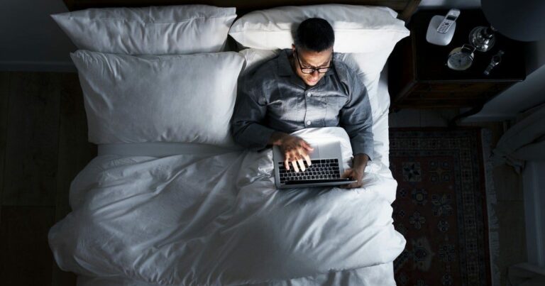 Man sitting in bed, learning how to become a Web Designer without coding skills.